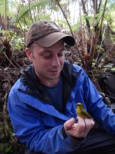 Logan Derderian, holding a bird in the forest.